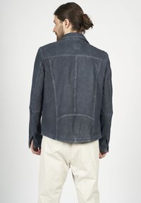 Marinblå läderjacka med en texturerad yta, skräddarsydd design och stickade detaljer. Har en vikbar krage och öppna manchetter.