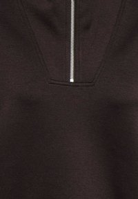 Črna majica s kapuco s četrtinskim zadrgo spredaj, izdelana iz mehke tkanine z gladko teksturo in subtilnim šivanjem okoli vratu.