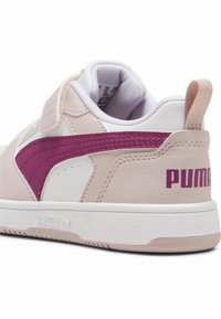 Le sneakers PUMA presentano una tomaia in pelle rosa con accenti bianchi, una striscia bordeaux e un logo PUMA sul tallone. Fascia in velcro per un facile indossamento.