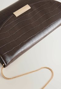 Braune Clutch aus Kunstkrokodilleder mit einem goldenen Metallverschluss und einem geflochtenen goldenen Kettenriemen. Glatte Textur mit glänzendem Finish.