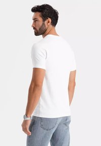 Hvid bomuld t-shirt med rund hals og korte ærmer, vist fra bagsiden, parret med lyseblå denimjeans.