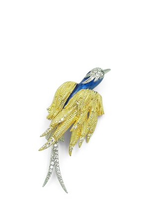 Spilla a forma di uccello con testa blu, ali dorate testurizzate e coda argentata decorata con piccoli gioielli trasparenti.