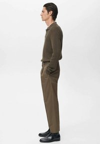 Brown ribbed knit polo shirt paired with beige pants and black ankle boots. Side view shows slim fit design and smooth textures.