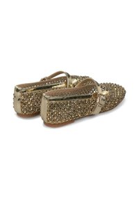 Chaussons plats dorés avec un design clouté et une finition brillante, bout arrondi et une bride ajustable au niveau de la cheville. Doublure intérieure lisse.