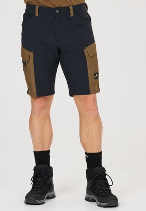 Homme portant un short cargo noir et marron avec plusieurs poches, des bottes de randonnée noires et des chaussettes noires.