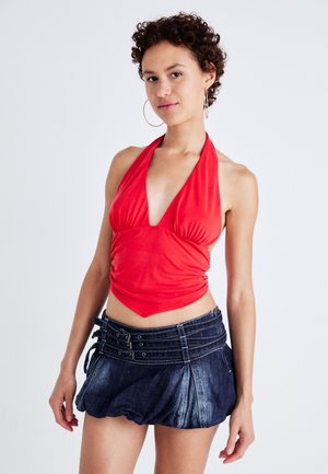 Červený halter top s nabíraným materiálem v kombinaci s tmavými džínovými mini sukněmi s rozšířeným střihem a několika přezkami.