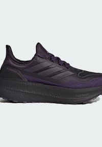 Chaussure de sport violette avec une tige respirante, des panneaux texturés et une semelle épaisse et rembourrée. Présente trois rayures caractéristiques sur le côté.