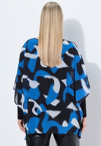 Top nero con motivo astratto blu e bianco. Tessuto leggero, design largo, fessure laterali e scollatura arrotondata.