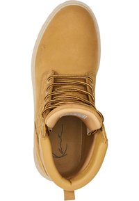 Brune ankelstøvle i ruskind med rund tå, tykke gule og brune snørebånd og sål i hvid gummi. Indvendig foring i beige tekstil.