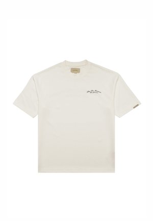 Cremefarbiges T-Shirt mit kurzen Ärmeln, rundem Ausschnitt und kleinem schwarzem Text "Pine De Monaco" auf der linken Brust.