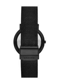 Montre en maille noire avec un boîtier rond noir, un verre transparent et une boucle portant le logo "Skagen". Sangle texturée et design minimaliste.