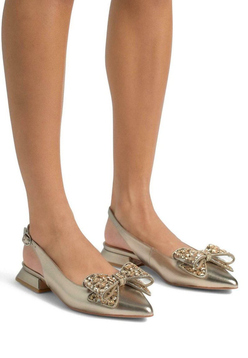 Ballerine slingback dorate con punte affusolate, decorate con un grande fiocco ornamentale con perline, su un tacco basso a blocco. Finitura metallica liscia.