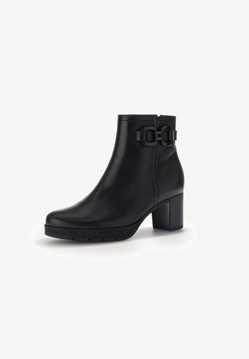 Bottine noire en cuir avec talon bloc et sangle décorative à boucle sur le côté, semelle robuste à crampons, fermeture éclair latérale.