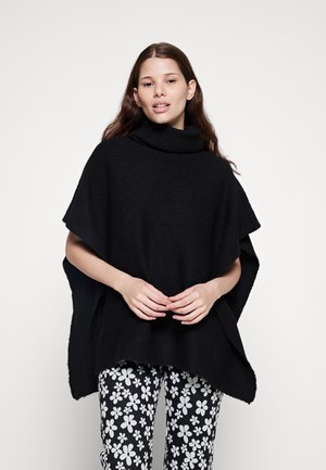 Poncho nero lavorato a maglia con colletto alto e maniche ampie. Abbinato a pantaloni con motivo floreale in bianco e nero. Tessuto morbido, vestibilità oversize.
