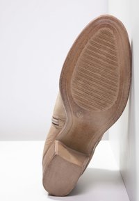 Beige nahka kengät, joissa on puinen korko ja teksturoitu kumi-pohja, näyttäen sileän yläosan ja erottuvan ompelukstin.