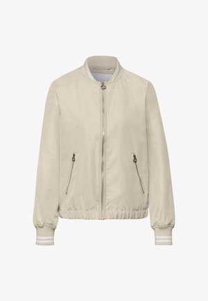Jasnobeżowa kurtka bomberka z przednim zamkiem błyskawicznym, dwoma zasuwanymi kieszeniami bocznymi, ściągaczem na kołnierzu, mankietach i dolnym brzegu z białymi paskami.