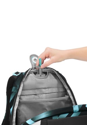 Hand pulling adjustable height key from inside backpack with blue and black geometric pattern.