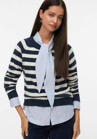 Un pull rayé bleu marine et blanc avec un col rond, des poignets côtelés et une écharpe bleu clair nouée au cou, superposé à une chemise bleu clair.
