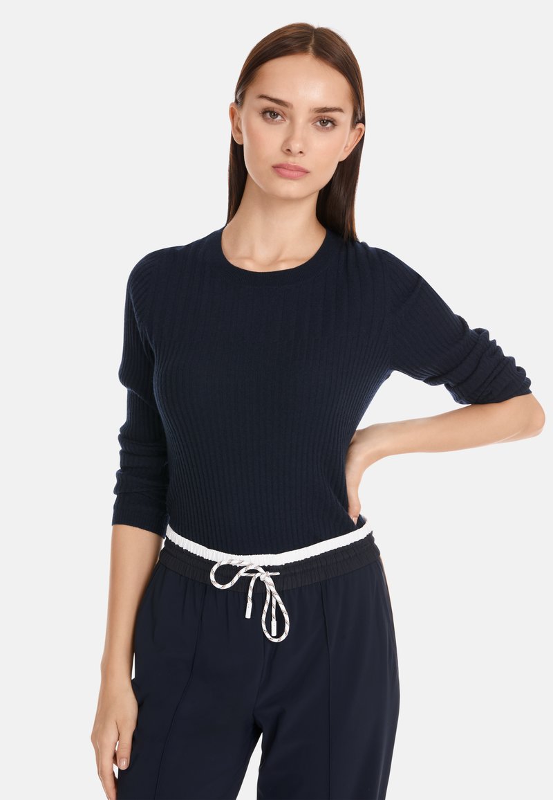 Marineblaues Rippenpullover mit Rundhalsausschnitt und Dreiviertelärmeln, kombiniert mit lässigen Hosen im lockeren Schnitt und einem weißen Kordelzugbund.