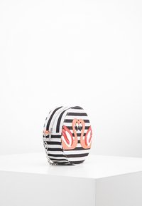 Pyöreä raidallinen laukku musta-valkoisena, jossa on vaaleanpunaisia joutsenkoristeita. Varustettu vetoketjulla ja ketjuhihnalla monipuolisuutta varten.