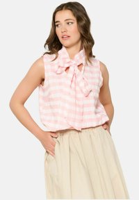 Gaiši rozā bez piedurknēm topiņš ar baltām svītrām, ar loku pie apkakles. Valkāts ar augsto vidukli beigu svārku. Mīksta auduma tekstūra.