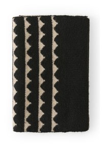 Tessuto a motivi neri e beige, con disegni a zigzag e superficie testurizzata. Forma rettangolare, materiale in stoffa morbida.