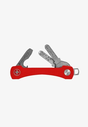 Multi-outil rouge avec une poignée courbée, outils en métal argenté incluant un ouvre-bouteille et un porte-clés, présentant une surface texturée sur les clés.