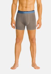 Braune Boxershorts mit einem blauen elastischen Bund, der mit "CR7" Branding versehen ist. Hergestellt aus glattem Material, passgenau für Komfort.