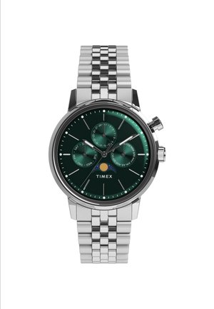 Montre en acier inoxydable argenté avec un cadran vert, trois sous-cadrans et un indicateur de date. Elle possède un bracelet à maillons texturé. Marque : Timex.