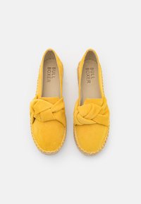 Espadrillas in suede giallo con design anteriore annodato, suola rifinita in juta e interno liscio. Presentano una forma della punta piatta e arrotondata.
