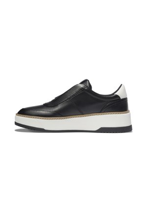 Sneaker slip-on in pelle nera con suola bianca spessa e linguetta bianca sul tallone, mostrata in profilo laterale su sfondo bianco.