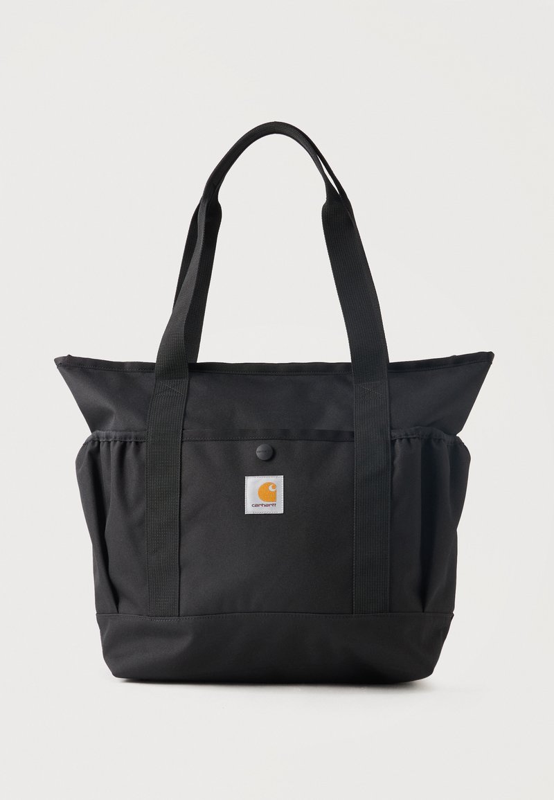 Zwarte Carhartt handtas met twee lange handvatten, voorvak met drukknop en logo-opdruk op een effen lichte achtergrond.
