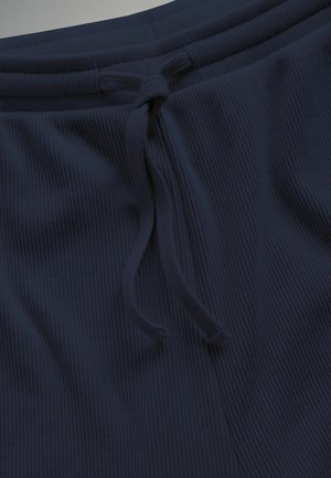 Nahaufnahme dunkelblauer, gerippter Stoffhose mit einem gebundenen Kordelzug am Bund.