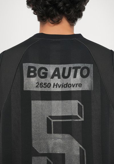 Crna sportska majica s velikim srebrnim grafičkim dizajnom koji sadrži "BG AUTO" i "2650 Hvidovre", uključuje i dizajn s prugastom teksturom.