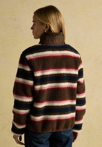 Braune, gestreifte Fleecejacke mit rosa, weißen und blauen Streifen. Hoher Kragen mit "JOULES" Stickerei. Weicher Stoff, lässige Passform.