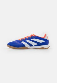 Zapatilla deportiva azul con rayas blancas, cordones naranjas y suela de goma. Presenta una textura suave y detalles perforados en la puntera.