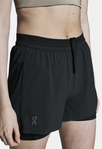 Zwarte sportkorte broeken van lichte stof, met een elastische tailleband met trekkoord en binnenvoering. Inclusief logodetail aan de zijkant.