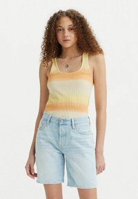 Gestreepte tanktop in gele en oranje tinten, gecombineerd met lichtblauwe denimshorts. De top heeft een geribbelde textuur en een vierkante halslijn.
