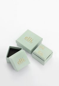 Trois boîtes à bijoux carrées vert clair avec texte doré "elli premium", une ouverte montrant l'intérieur noir, sur fond blanc.