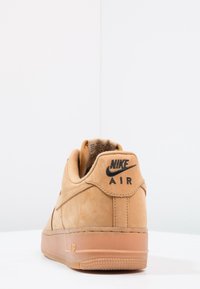 Tan Nike Air -sneakerit, joissa on mokkanahka materiaali. Pyöreä muoto, pehmeä kaulus ja musta logo kantapäässä. Raskaasti kaiverrettu kumipohja.
