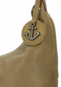Borsa a mano in pelle marrone chiaro con forma arrotondata, superficie liscia e un'etichetta circolare in pelle con un emblema ancorato metallico.