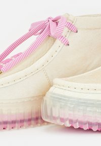 Chaussures en cuir beige à lacets avec lacets rose zigzag. Semelle translucide avec un dégradé du clair au rose. Détails de couture texturée.