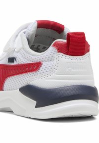 Baskets blanches avec des accents rouges et navy, dessus en maille, semelle texturée et une languette au talon pour un enfilage facile.