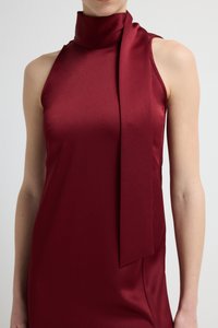 Bordowa sukienka bez rękawów z wysokim kołnierzem i zawiązywanym bokiem. Wykonana z gładkiej, satynopodobnej tkaniny o matowej fakturze.