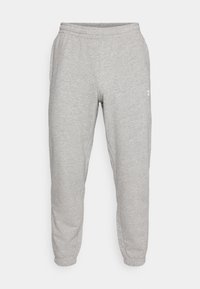 Hellgraue Sweatpants mit elastischem Bund und Bündchen, seitlichen Taschen und kleinem weißem Logo am oberen Oberschenkel.