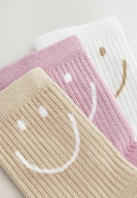 Drei Paar gerippte Socken in Beige, Pink und Weiß, jeweils mit einem Smiley-Gesicht-Design in weißem oder braunem Stickerei.