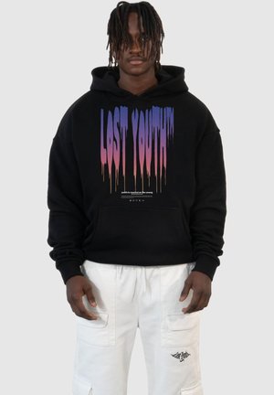 Black hoodie featuring "LOST YOUTH™" graphic in dripping gradient colors, paired with white cargo pants with pockets.