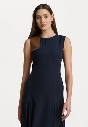 Abito blu navy con design senza maniche e un accento in pelle marrone sulla spalla sinistra. Il materiale appare liscio con una sottile lucentezza.