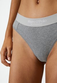 Mutande grigie a coste con un ampio elastico in grigio chiaro che presenta il marchio "Marc O'Polo". Il tessuto appare morbido ed elastico.