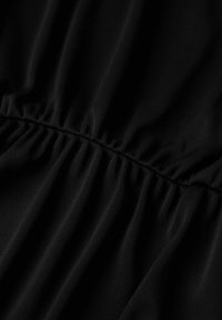 Tejido negro con una textura suave, que presenta costuras recogidas a lo largo del centro, creando pliegues suaves y fluidos.